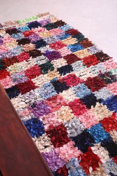 a crocheted rug is laying on the floor next to a wooden table and chair