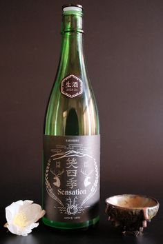 a bottle of wine sitting on top of a table next to a bowl and flower