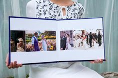 a woman holding an open photo book with pictures of people on it in front of her