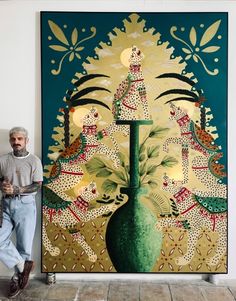 a man standing in front of a painting on the wall next to a tall green vase