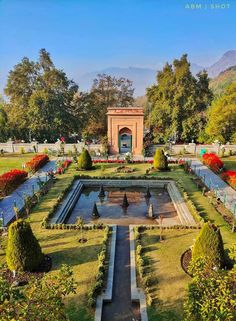 the garden is full of beautiful flowers and greenery, with a fountain in the middle