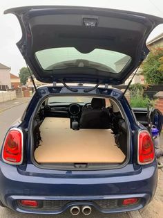 the back end of a blue car with its trunk open