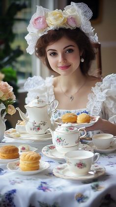 a woman sitting at a table with tea and pastries