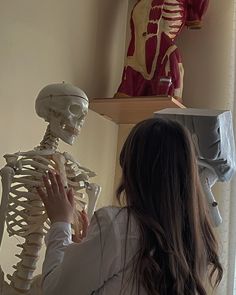 a woman standing in front of a skeleton and looking at it's back end