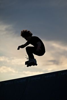 a skateboarder in the air doing a trick on a ramp at sunset or dawn