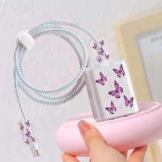 a person is holding a pink device with butterflies on it and an extension cord to the phone