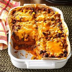 a casserole dish with meat and cheese in it sitting on a table next to a napkin