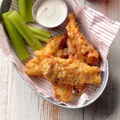 a plate filled with chicken wings and celery sticks next to ranch dips