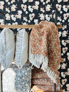 an assortment of pillows and blankets hanging on a rack