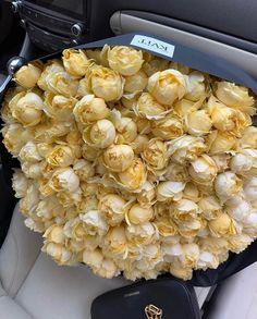 a bunch of yellow flowers sitting in the back seat of a car with a tag on it