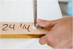 a person holding a pair of scissors in front of a wooden sign