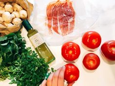 tomatoes, parsley and mushrooms are on the counter next to a bottle of olive oil