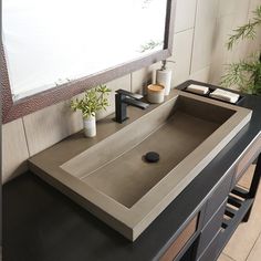 a bathroom sink sitting under a mirror next to a counter top with a plant on it