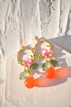 "AMALFI crown translucent tangerine orange earrings, czech glass tangerine earrings, food earrings, mandarin fruit earrings, custom earrings These Tangerine Crown of Flowers Gold Plated Earrings are a stunning piece of jewelry that will instantly elevate any outfit. The earrings feature delicate gold plating that forms a crown-like design, adorned with beautiful flowers and leaves. The centerpiece of the earrings is a dazzling transluscent tangerine orange( or mandarin) Czech crystal, adding a pop of color and sparkle to the design. These earrings have a timeless elegance that will transport you to the picturesque Amalfi Coast in Italy with every wear. Whether you're dressing up for a special occasion or simply adding a touch of glamour to your everyday look, these earrings are sure to tur Nickel Free Orange Jewelry For Party, Nickel-free Orange Jewelry For Party, Orange Drop Earrings For Gift, Cute Orange Jewelry For Party, Cute Nickel-free Orange Jewelry, Cute Orange Party Jewelry, Orange Dangle Flower Earrings Gift, Orange Dangle Flower Earrings For Gift, Orange Dangle Flower Earrings With Ear Wire