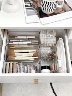 an open drawer with various items in it and pictures on the bottom shelf above them