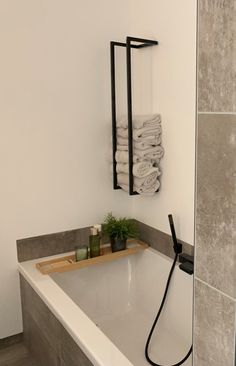 a white bath tub sitting next to a wooden shelf with towels on top of it