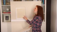 a woman is painting a wall with white paint and she has her hands on the board