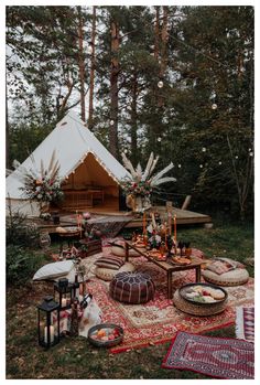 a tent is set up in the woods for an outdoor party with food and decorations