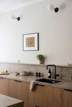 a kitchen with marble counter tops and wooden cabinets, along with black faucets