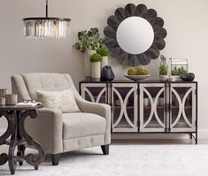 a living room with a chair, table and mirror on the wall next to it