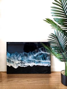 a plant in a pot next to a television on a wooden table with a white wall behind it