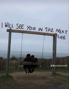 two people sitting on a bench under a sign that says i will see you in the next life