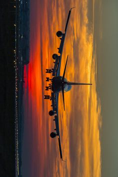 an airplane is flying in the sky at sunset or sunrise with clouds reflecting on the water