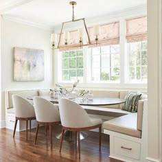 a dinning room table with four chairs and a bench in front of the window