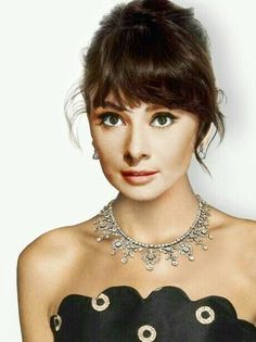 a woman in a black dress with a necklace and earrings on her neck is posing for the camera