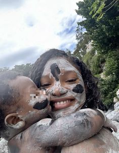 two children covered in mud with their faces painted black and white, one holding the other's head