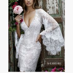 a beautiful woman in a white dress holding a pink rose and posing for the camera