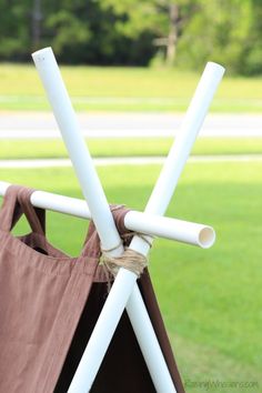 two white poles sticking out of the side of a brown and white chair in front of a grassy field