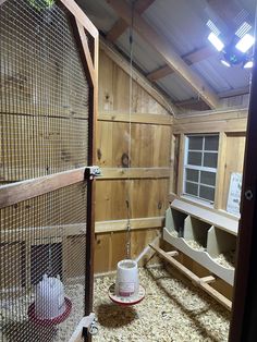 the inside of a barn with hay on the floor and an animal cage in it