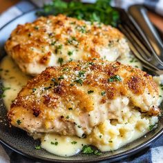 two pieces of chicken breast covered in gravy and garnished with parsley