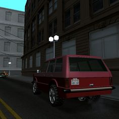 a red car driving down a street next to tall buildings