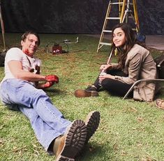 two people sitting in the grass with paint on their faces and one holding an apple