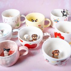 there are many cups with dogs and cats in them on the table next to each other