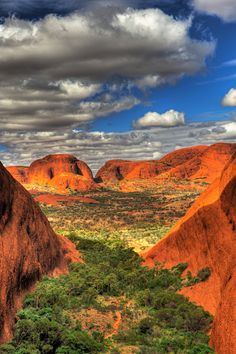 the landscape is very colorful and has many trees in it's foreground, as well as clouds above them