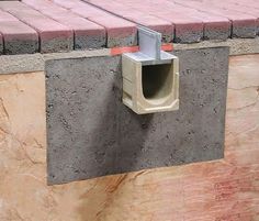 a cement box attached to the side of a brick wall with a concrete block on it