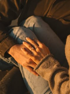 a person sitting down with their hand on the other side of his arm, wearing a ring