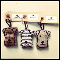 three key chains with dogs on them hanging from hooks in front of a white wall