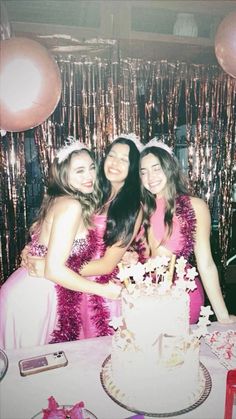 three women standing next to each other in front of a cake