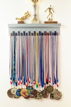 a wall mounted medal rack with medals and trophy cups on it's sides in front of a white wall