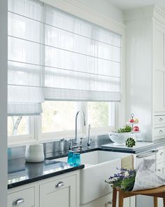 a kitchen with white cabinets and black counter tops