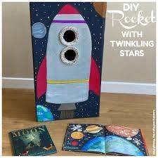 a cardboard box with an image of a rocket on it and three books in front