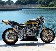 a black and gold motorcycle parked next to the water