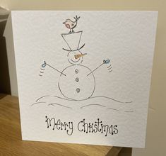 a white card with a drawing of a snowman on it and the words merry christmas