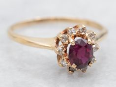 a gold ring with an oval shaped ruby stone surrounded by small white and brown diamonds