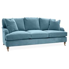 a blue couch with four pillows on it's arms and legs, against a white background