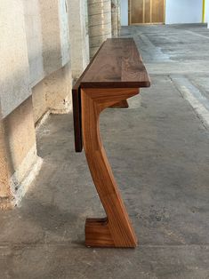 a wooden table sitting on top of a cement floor next to a wall and doorway